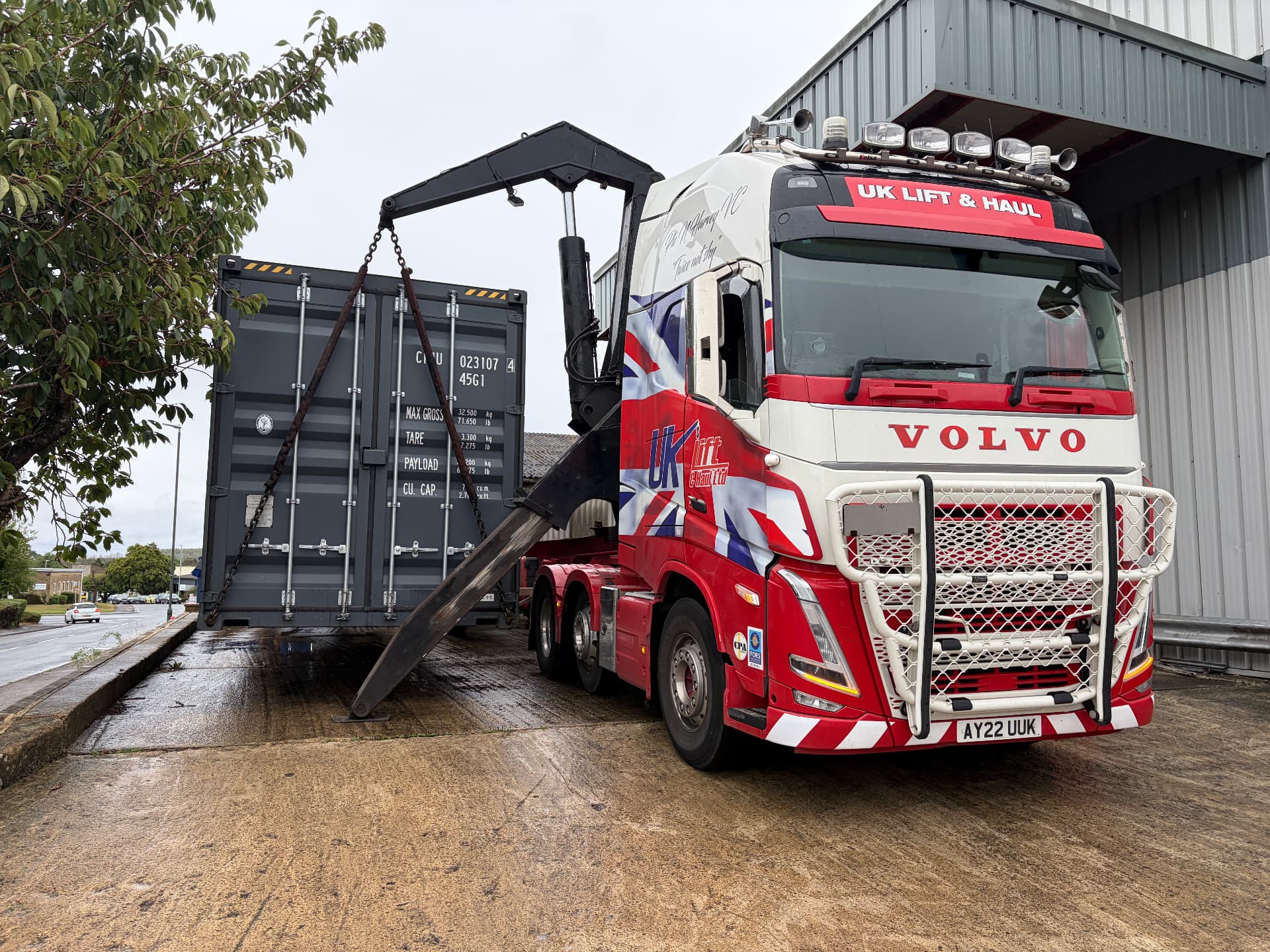 A 40ft unmodified shipping container being lifted off a delivery lorry at the drop-off site