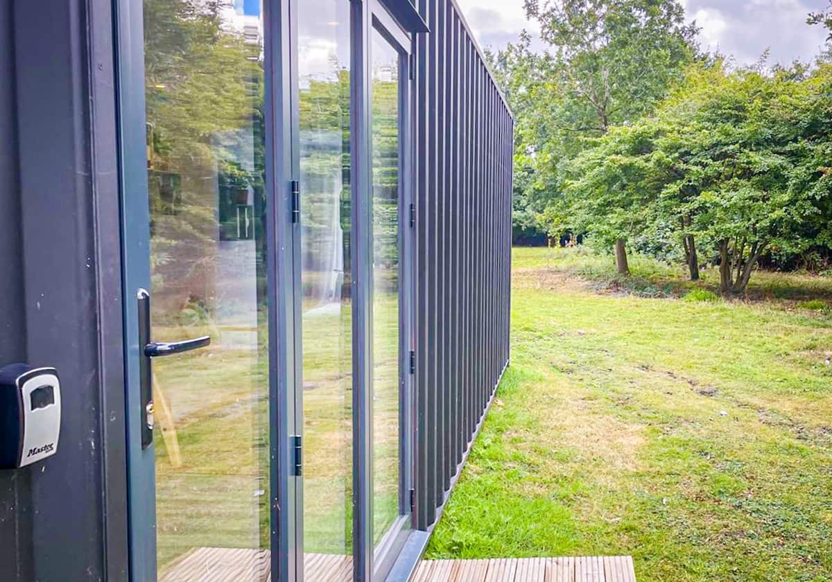 Living and sleeping space inside the Marshwood Eco Pod shipping container conversion, looking out to woodland