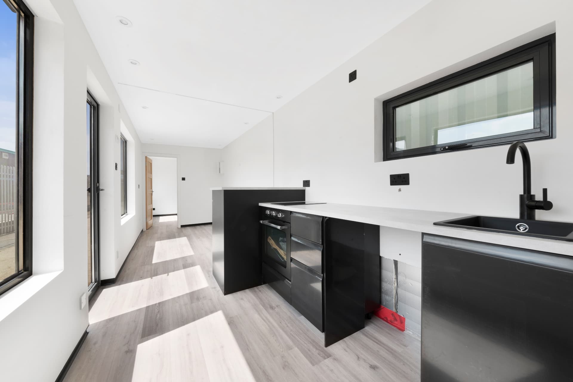 Fitted kitchen with black units and stone worktop inside a 40 ft container conversion