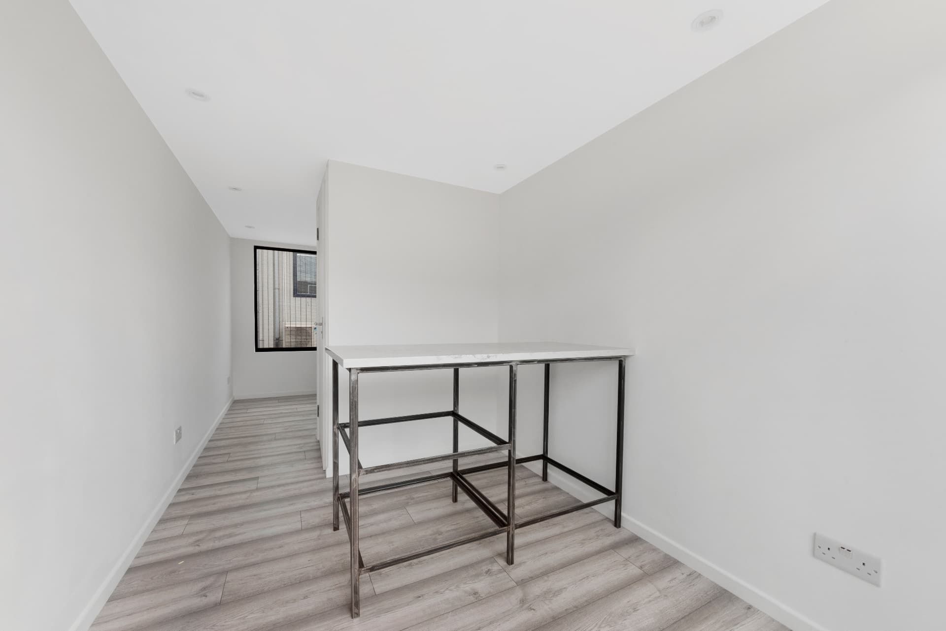 White plastered interior of a 20 ft container with breakfast bar and engineered flooring