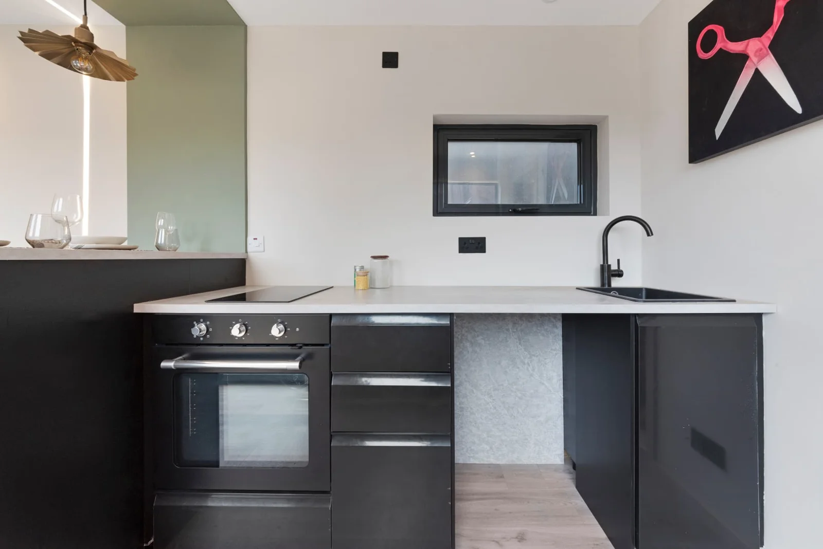 Residential Unit 27 fitted kitchen with black cabinetry, oven, hob and sink