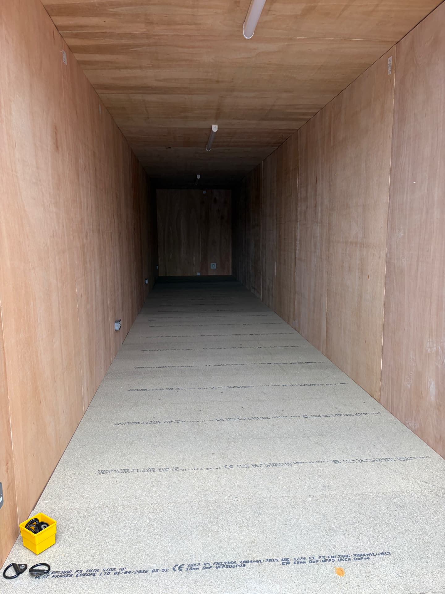 Interior of an unmodified 40ft shipping container lined with plywood walls and a composite floor